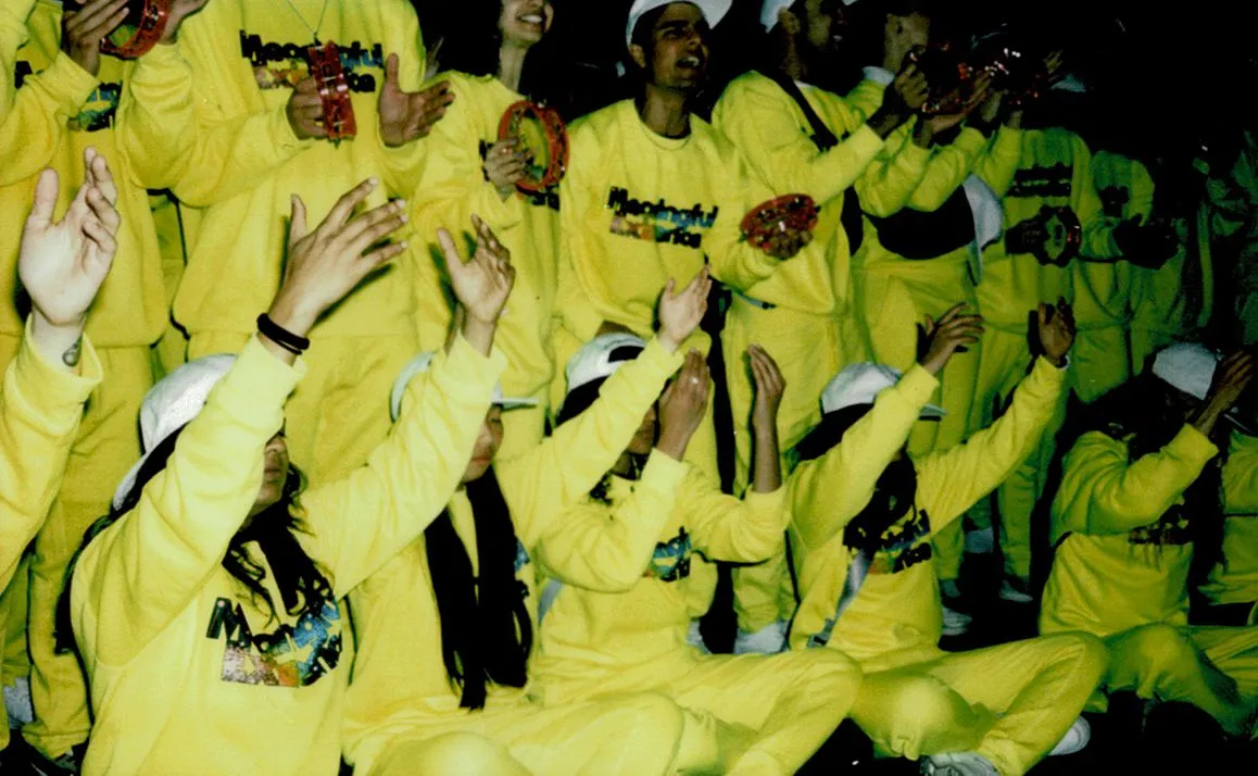 A group of Meaningful Existence devotees performing a spiritual song, hands raised in adoration.