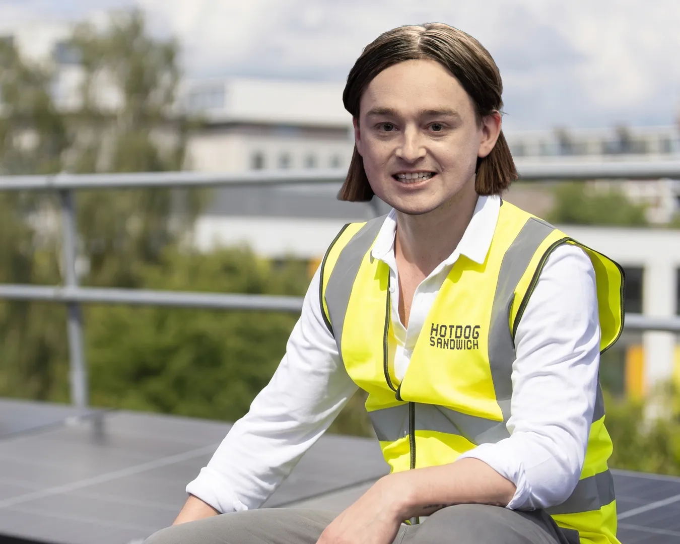Spencer in a high-vis vest smiling, crouched at a construction site.